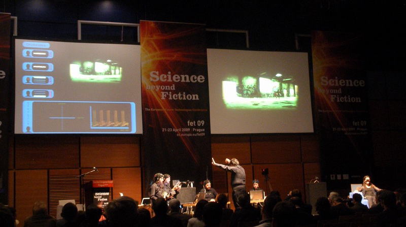 The Brain Orchestra on stage: performers wearing EEG caps in front of a screen